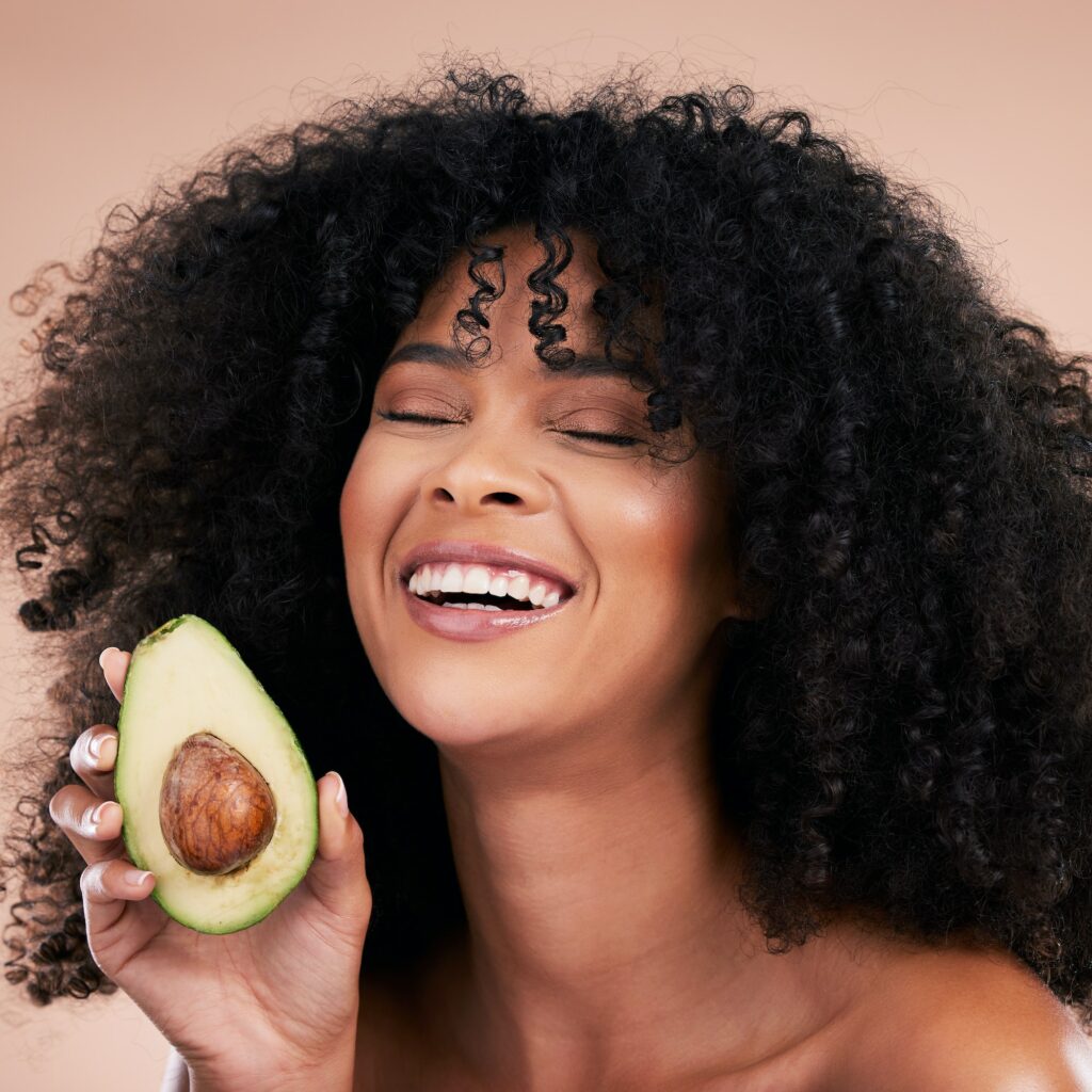 Black woman, studio and avocado for beauty, smile and skincare with health, wellness and self care
